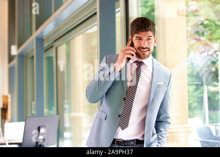 Portrait shot of successful businessman wearing suit while making a business telephone call in the office. Stock Photo