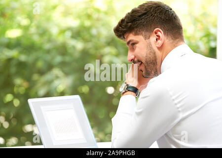 Rear view shot of confident businessman wearing shirt and tie while working on his laptop at office desk. Stock Photo