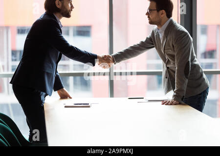 Confident serious two businessmen shaking hands at office. Stock Photo