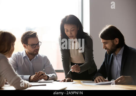 Older asian busineswoman sharing project ideas to workers. Stock Photo