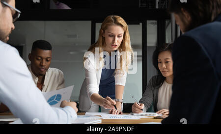 Young businesswoman explaining research results in graphs to colleagues. Stock Photo