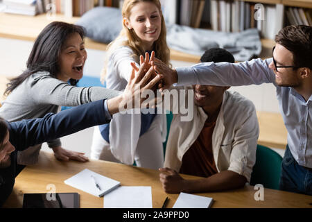 Happy multiracial younger and older colleagues joining hands. Stock Photo