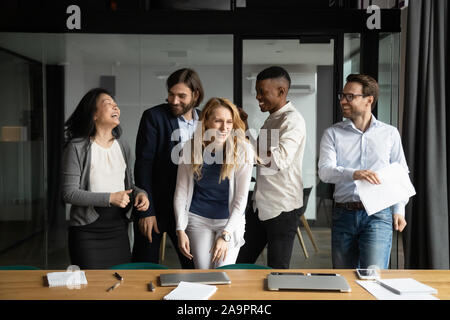 Overjoyed diverse colleagues having fun after workday at office. Stock Photo