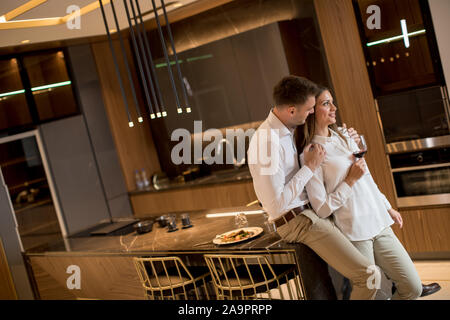 Sweet young couple drinking red wine after romantic dinner at luxury kitchen Stock Photo