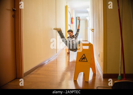 Man slips on wet floor. Wet floor danger sign in the foreground. Concept of danger slipping Stock Photo