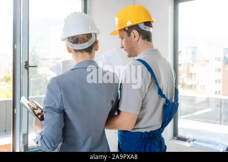 Construction worker and architect looking at plan on site Stock Photo