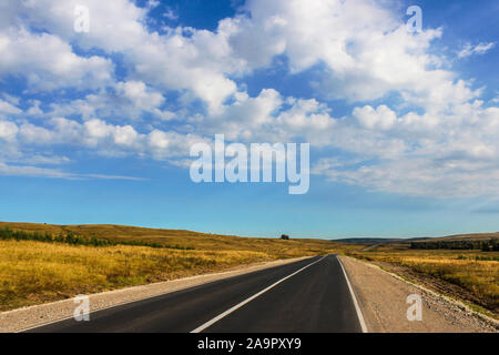 Landscape overlooking the road leading through fields and hills Stock Photo