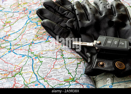 Car key and gloves on a road map or atlas. Stock Photo