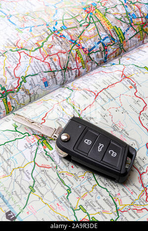 Car key laying on a road map or atlas. Stock Photo
