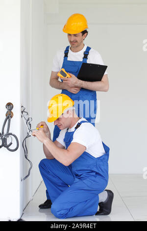 Electrician stripping electrical wires for wall socket Stock Photo