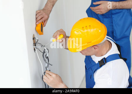 Electrician stripping electrical wires for wall socket Stock Photo