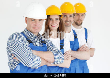 A friendly young team of construction workers with arms crossed standing in a row and smiling Stock Photo