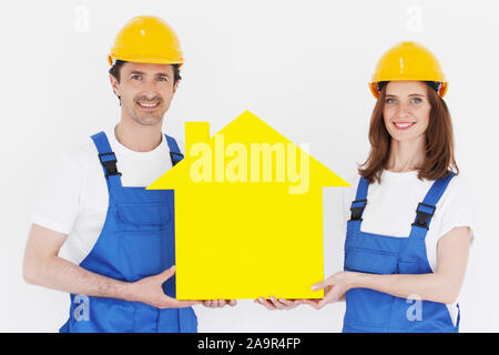 Two happy smiling workers hold yellow house model outdoors at construction site Stock Photo