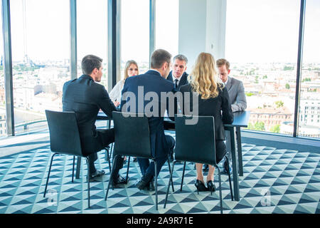 Executives participating in meeting taking seat at office table. Panoramic window with view on city on background Stock Photo