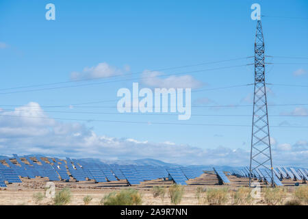 solar panels with tracker field for generating sustainable energy with an electric mast in the foreground for transporting the generated electricity, Stock Photo