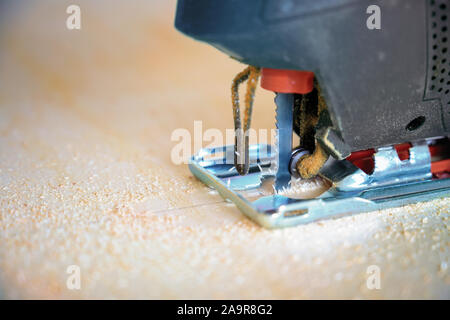 Close-up detail of an electric jigsaw sawing up a plywood board, tool for professional or hobby craft work, copy space, selected focus, very narrow de Stock Photo