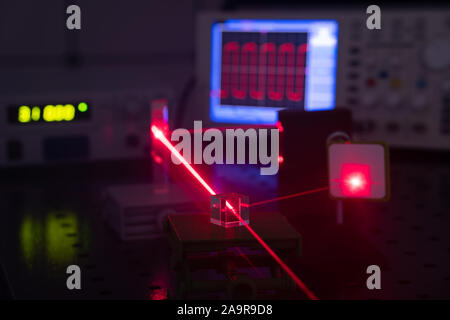 Experiment in optic lab with laser device. Red laser on optical table in physics laboratory Stock Photo