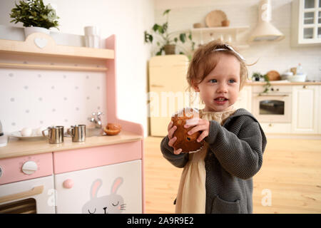 Happy child concept. Adorable baby girl with homemade cake in white designer kitchen place Stock Photo