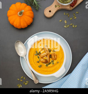 Creamy carrot soup, autumn foods. Spicy, roasted vegetable soup in bowl. Dark background. Square iamge. Stock Photo