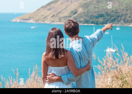 Love, travel, tourism and people concept - couple on vacation standing on mountain, hugging and pointing finger Stock Photo