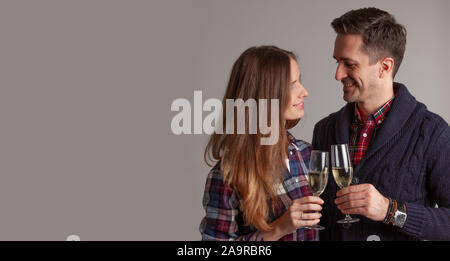 Happy mature couple in casual clothes embracing and clinking glasses of champagne Stock Photo