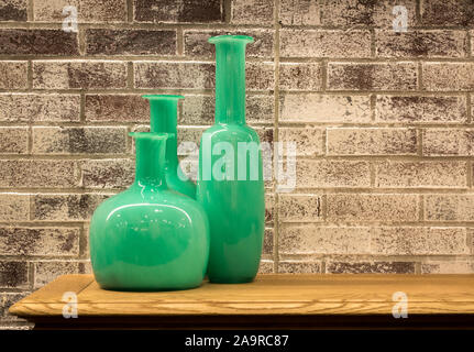 3 retro green glass vases against a wall made from vintage reclaimed bricks with copy space Stock Photo