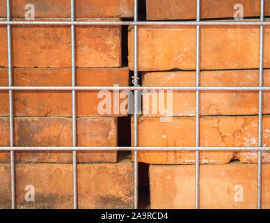 background texture-close up of vintage reclaimed red bricks stacked in a metal cage Stock Photo