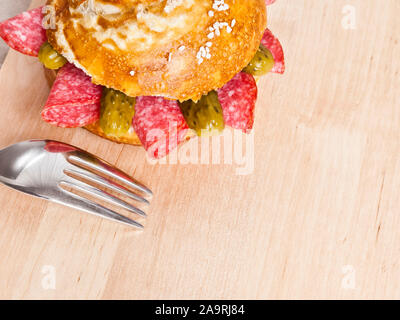 german bread roll with salami slices on a wooden plate Stock Photo