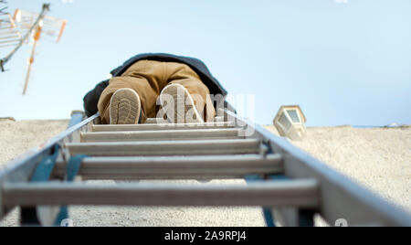 Low angle view of a handyman climbing on a steel ladder. Stock Photo