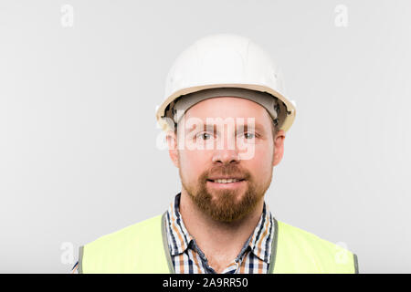 Portrait of young successful builder in white hardhat and workwear in isolation Stock Photo
