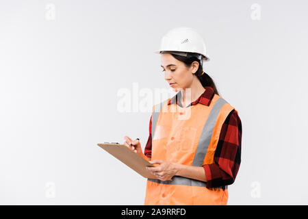 Female builder in hardhat, flannel and working vest making notes in document Stock Photo