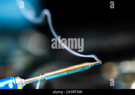 soldering iron with smoke on a black background. Electrical, electronics Stock Photo