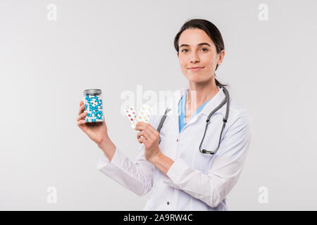 Pretty young clinician showing you bottle of pills and blisters with tablet Stock Photo