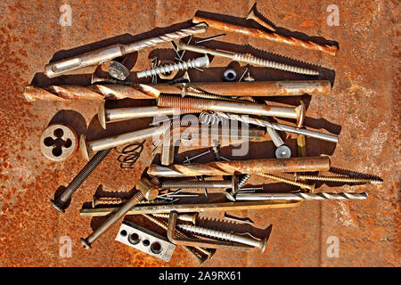 Many different steel and other metal objects on the rusty iron sheet close-up, in bright sunlight Stock Photo