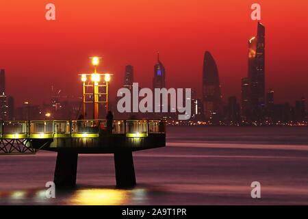 Kuwait City/Kuwait - 10/10/2019: Pier at sunset with skyline silhouette of Kuwait City in the background Stock Photo