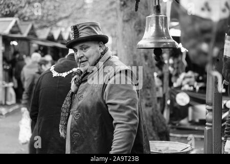 Male Market Trader wearing a leather waistcoat and hat selling hot Horse Chestnuts at Harrogate Christmas Market, North Yorkshire, England, UK. Stock Photo