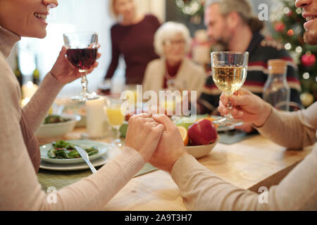 Hands of young affectionate couple with glasses of wine making festive toast Stock Photo