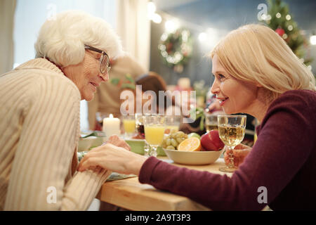 Senior woman in eyeglasses and her blonde daughter chatting by served table Stock Photo