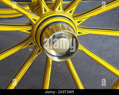 bright yellow & black spokes and axle with brass hub of wooden wheel of historic carriage in a collection in England, UK Stock Photo