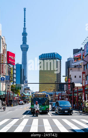 Traffic waiting at pedestrian crossing in Asakusa with the Tokyo Skytree tower and golden building, Asahi beer headquarters, in the distance. Blue sky Stock Photo