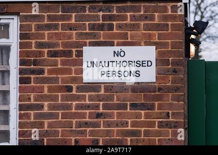 'No Unauthorised persons' sign board on a wall with black text on white background board Stock Photo