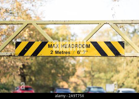 Headroom height restriction enforcement with signage and iron bars across two poles to reduce abuse of parking space Stock Photo