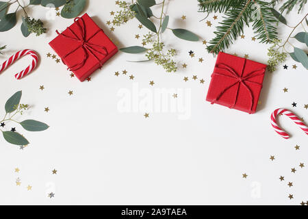 Christmas floral frame, web banner. Fir, berry eucalyptus tree branches, red gift boxes, red gift boxes and golden confetti stars isolated on white Stock Photo