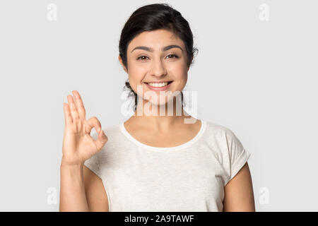 Head shot portrait smiling beautiful Indian girl showing ok gesture Stock Photo
