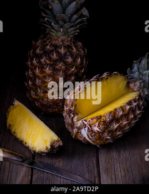 Sliced pineapple on old rustic desk Black background. Stock Photo