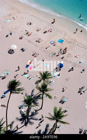 Sunbathers stretch out on the white sands of famous Waikiki Beach that is among the most popular destinations for vacationers who come to the capital city of Honolulu on Oahu, one of the eight major islands in the Pacific Ocean that are part of the tropical state of Hawaii, USA. This aerial photograph shows only a small part of Waikiki Beach, which is two miles (3.2 kilometers) long and actually has eight sections with individual beach names. More populated are the sands and walking promenades in front of historic and high-rise hotels along the meandering shoreline. Stock Photo