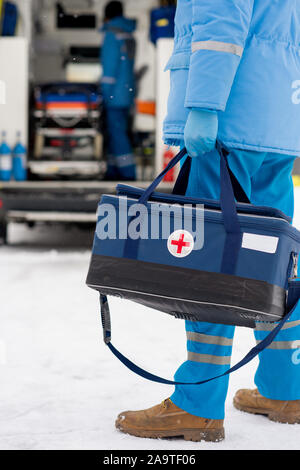 Young paramedic in blue workwear and medical gloves carrying first aid kit Stock Photo