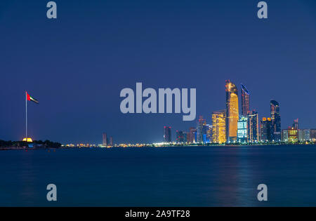 Abu Dhabi downtown night skyline reflected in the seaside, capital city of the UAE Stock Photo