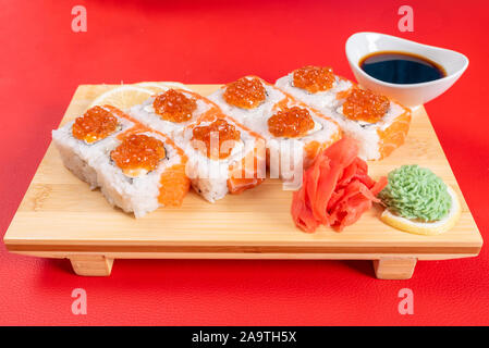 Sushi, with curd cheese, salmon and caviar. On the plank. On a red background. Stock Photo