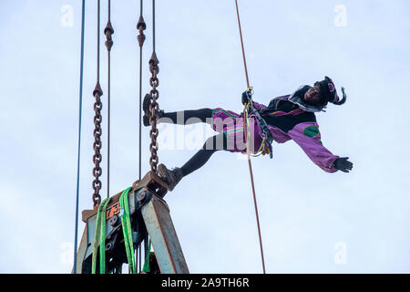 ENSCHEDE, THE NETHERLANDS - NOV 16, 2019: Two black peter’s’ the helping hand of the dutch Santa Claus’ are climbing in a crab crane. Stock Photo